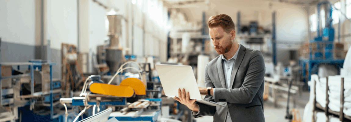 man holding computer in manufacturing facility